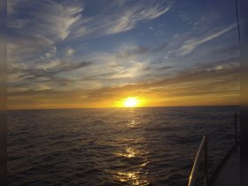 A stunning sunset over calm waters, captured from the deck of a boat, creating a serene backdrop perfect for evening cruises.