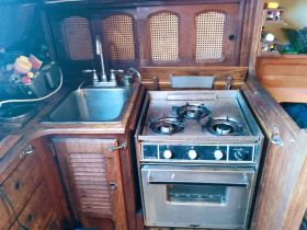 Interior view of a boat kitchen featuring a sink and a stove, showcasing the cozy and functional design of onboard living spaces.