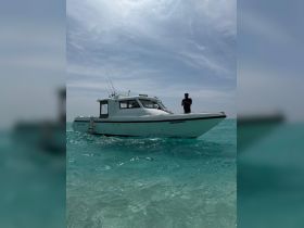 A sleek boat navigates through crystal-clear waters, showcasing its design and functionality. Ideal for fishing or leisure trips in tropical destinations.