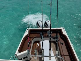 A well-equipped fishing boat featuring multiple fishing rods and a comfortable seating area, perfect for a day out on the water.