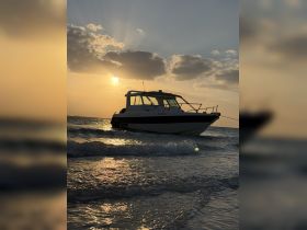 A serene sunset view of a boat anchored on the shore, reflecting the golden hues of the setting sun — perfect for capturing the tranquility of a day on the water.