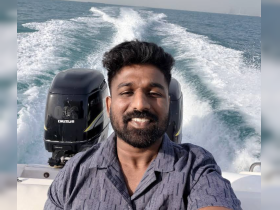 A joyful selfie of a man enjoying a boating experience, capturing the thrill of being on the water with the boat's wake in the background.