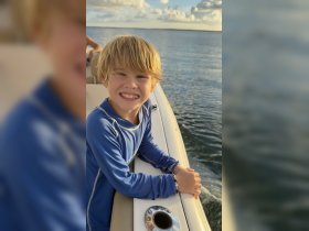 A cheerful child enjoys the boat ride, capturing the joy of family outings on the water.