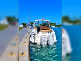 A stunning view of the 'Osiris' yacht docked at the marina, showcasing its sleek design and powerful twin engines against a clear blue sky.