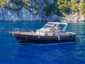 A beautiful yacht anchored in crystal-clear waters, surrounded by stunning rocky cliffs, perfect for exploring coastal destinations.