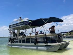 A lively group enjoys a sunny day aboard a pontoon boat, perfect for outdoor adventures and water activities.
