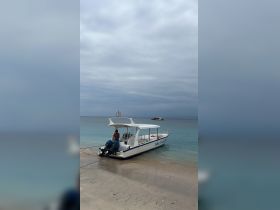 A speedboat named 'Nisa Paradise' is docked on the beach, with a person visible on board, showcasing a perfect spot for water adventures.