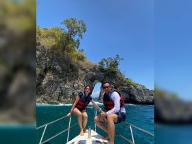 A couple enjoys a scenic boat ride near a stunning rock formation, showcasing the beauty of ocean adventures. Perfect for those seeking memorable experiences on the water.