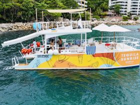 The 'Tequila Sunrise' catamaran is docked in Puerto Vallarta, showcasing its vibrant design and spacious layout, perfect for group tours and celebrations on the water.
