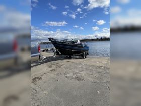 A sleek speedboat is docked at the ramp, ready for launch into the water, showcasing its polished exterior against a clear blue sky.