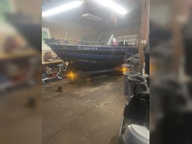 A well-maintained fishing boat is showcased in a garage, highlighting its console and interior features, perfect for enthusiasts looking to upgrade their vessel.