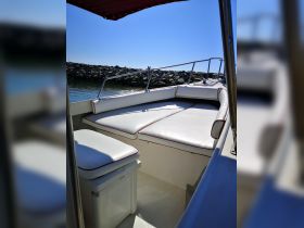A clean and spacious interior view of a boat's seating area, featuring comfortable cushions and a cooler, perfect for relaxing on the water.
