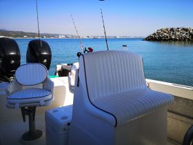 Interior view of a fishing boat showcasing comfortable seating and helm area, perfect for a day on the water.