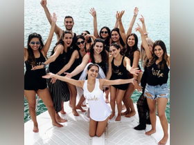 A lively group celebrates a bachelorette party on a boat, showcasing joy and camaraderie against a beautiful water backdrop.