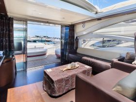 Interior view of a luxurious yacht cabin featuring comfortable seating and large windows, perfect for relaxing while enjoying the marina views.
