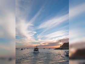 A picturesque sunset scene featuring boats navigating the ocean, capturing the essence of a vibrant boating experience.