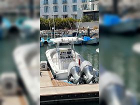 A well-equipped center console boat docked at a marina, showcasing its sleek design and powerful twin engines, perfect for fishing or day trips on the water.