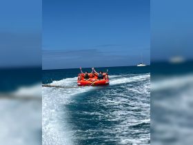 A thrilling moment as two friends enjoy tubing in the clear blue waters, showcasing the excitement of water sports on a sunny day.