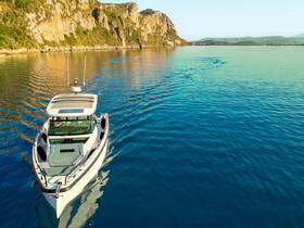 An aerial view of a sleek speedboat gliding through calm waters, surrounded by stunning cliffs — perfect for exploring coastal landscapes.