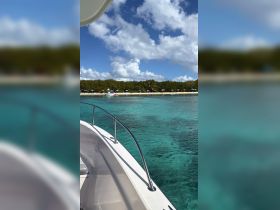 A stunning view from the bow of a boat, showcasing the vibrant turquoise waters and a picturesque beach lined with umbrellas — perfect for a day of relaxation and exploration.