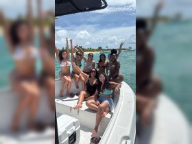 A lively group of friends celebrates on a boat, enjoying the sun and water — perfect for a fun day out on the ocean.