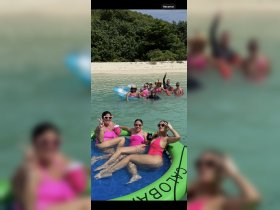 A lively group of friends enjoys a fun day at the beach, relaxing in the water and on inflatable floats — perfect for summer celebrations and beach parties.