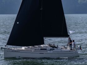A catamaran named 'Cat Balou II' sails gracefully on the water with two individuals on deck, showcasing the joy of sailing adventures.