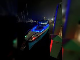 A vibrant speedboat illuminated with colorful lights docked at night, showcasing its sleek design and perfect for evening outings on the water.