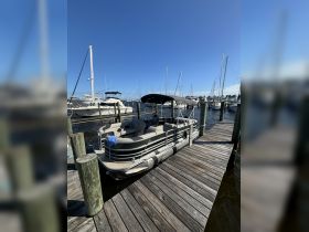 A pontoon boat docked at the marina, showcasing its spacious design and comfortable seating, perfect for leisurely outings on the water.