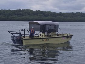 A fishing boat named 'Sol y Sal' navigates through calm waters, showcasing a serene boating experience amidst lush greenery.