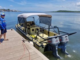 A child stands by a boat at the dock, ready for an exciting day on the water. The vibrant scenery and calm waters set the stage for a memorable boating adventure.