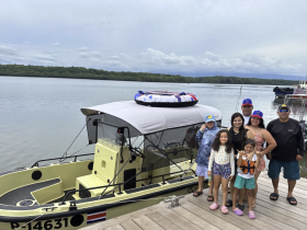 A cheerful family poses together on the dock beside their boat, ready for a fun day on the water. Perfect for family outings and adventures.