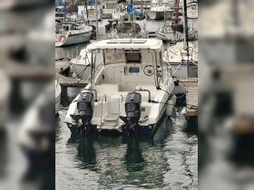 A clear view of a speedboat docked at the marina, showcasing its sleek design and twin outboard motors, perfect for water adventures.