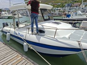 A person adjusts the canopy on the Ocean Master boat docked at the marina, showcasing its sleek design and readiness for adventure.