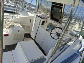 Inside view of a boat's helm area, showcasing the steering console and seating, ideal for navigating the waters.