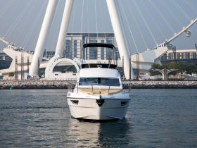 A stunning front view of a yacht docked near a modern architectural landmark, showcasing the elegance of boating in a vibrant urban setting.