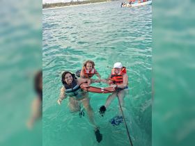 A joyful group of friends enjoys a fun swimming experience in the clear ocean waters, wearing life jackets for safety. Perfect for adventure seekers looking to make unforgettable memories on the water.