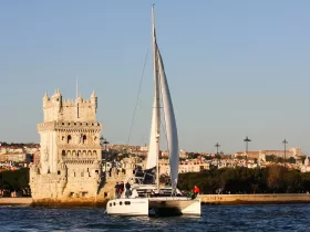 A catamaran sails past the iconic Belém Tower in Lisbon, showcasing a beautiful blend of maritime adventure and historic architecture.