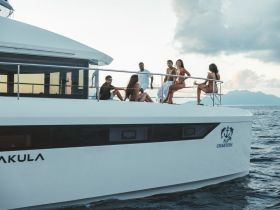 A lively group enjoys their time aboard a luxurious yacht, sharing drinks and laughter against a stunning ocean backdrop — perfect for celebrations and memorable outings.