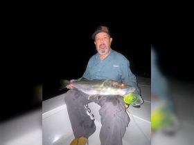 An angler proudly displays a freshly caught snook during a night fishing trip, showcasing the thrill of fishing under the stars.