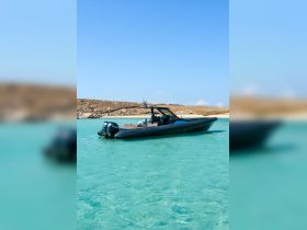 A sleek speedboat anchored in crystal-clear waters, showcasing its elegant design against a picturesque backdrop of sandy shores.