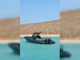 A sleek speedboat glides through clear turquoise waters, showcasing its modern design against a serene backdrop of sandy shores.