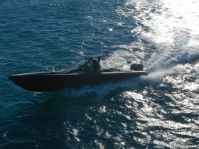A sleek speedboat cuts through the shimmering waters, showcasing its dynamic design and performance while underway.