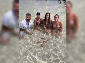 A joyful group of friends interacts with starfish in shallow waters, capturing a memorable wildlife experience in a tropical paradise.