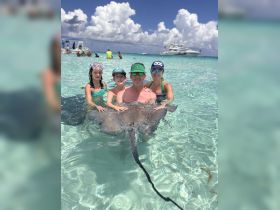 A family interacts with a stingray in shallow waters, creating a memorable wildlife experience during their aquatic adventure.