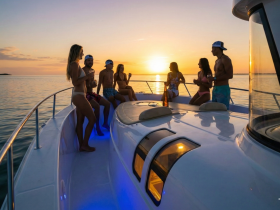A lively group enjoys a sunset celebration on a yacht, sipping cocktails and soaking in the beautiful views — perfect for unforgettable moments on the water.