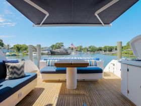 A beautifully designed lounge area on a boat, featuring comfortable seating and a scenic view of the marina — perfect for relaxing and enjoying the water.