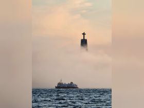 A serene view of a boat navigating through foggy waters with a prominent landmark in the background, creating a mystical atmosphere perfect for capturing the beauty of maritime adventures.