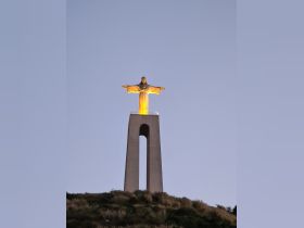 A view of the iconic Christ the Redeemer statue illuminated against the evening sky, showcasing a significant landmark in Rio de Janeiro.