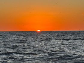 A stunning sunset over the ocean, creating a picturesque backdrop for a serene boating experience.